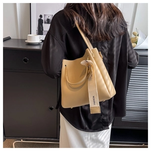 Detail of beige bucket bag with vertical pleats and Fashion ribbon strap held by model