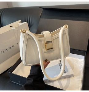Detailed view of white wavy textured handbag with golden lock and luxury gift packaging