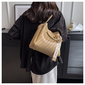 Close-up of beige leather bucket bag featuring fashion strap and protective metal feet