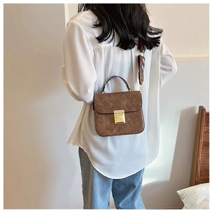 Detail view of brown vintage texture small square bag with colorful wide shoulder strap