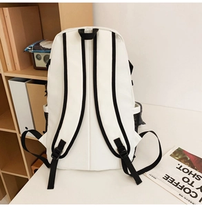 Detail of white canvas backpack featuring adjustable black straps and side mesh pockets