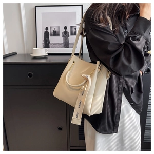 Detail of cream white bucket bag featuring premium leather texture and fashion webbing strap