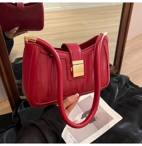 Detail of red embossed leather bag with golden hardware and elegant wave pattern texture