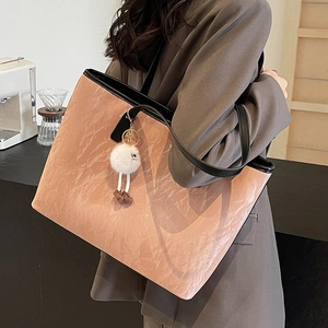 Pink pleated tote bag with black straps and plush charm shown on a female model