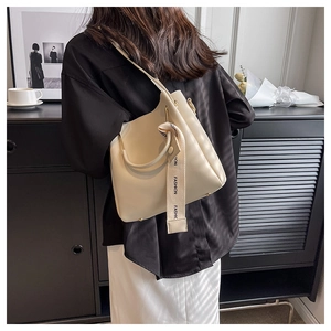 Detail showing cream-colored PU leather bucket bag with fashion strap and metal studs
