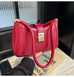 Detail of red wedding handbag featuring textured wavy leather and a golden square lock clasp
