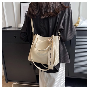 Detail of cream white bucket bag with a fashion text woven strap and metal hardware