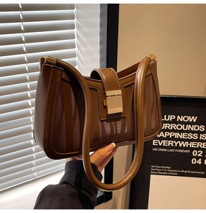 Detail of dark brown V-stripe embossed leather shoulder bag with gold clasp and long strap