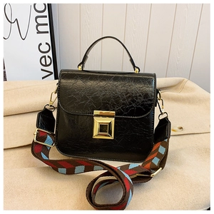 Detail of black textured crossbody bag with wide colorful geometric fabric strap