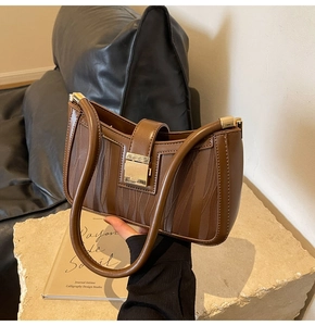 Detail of coffee brown handbag featuring gold square lock and wavy textured fabric panels