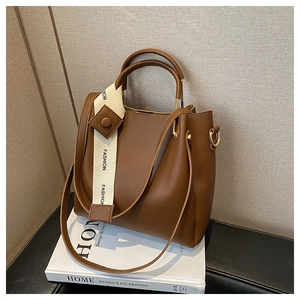 Detail view of large dark brown tote bag with fashion ribbon and round handles