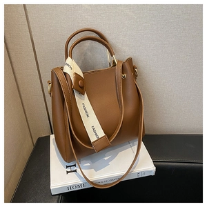 Detail of brown leather bucket bag with curved handle and Fashion decorative ribbon