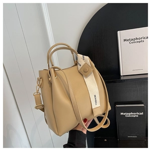 Detail of beige faux leather bucket bag with fashion webbing strap and round handle