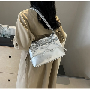 Close-up of silver tote bag with metallic bow details and DOROTHY brand lettering