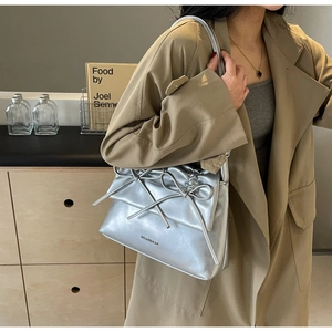 Close-up of silver baguette shoulder bag featuring a 3D bow tie design and metallic finish