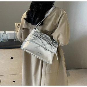Close-up of silver tote bag with ribbon bows and embossed logo on soft metallic leather