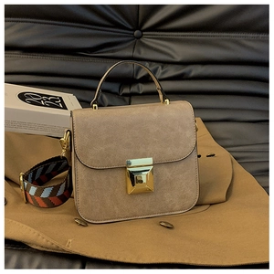 Detail of khaki PU leather bag with gold twist lock and colorful geometric strap