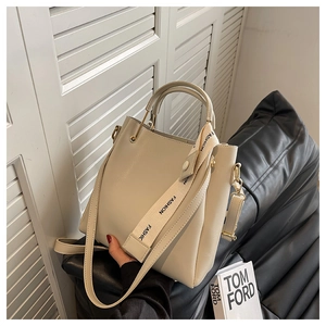 Detail of cream leather tote bag with fashion print strap and gold-tone metal hardware