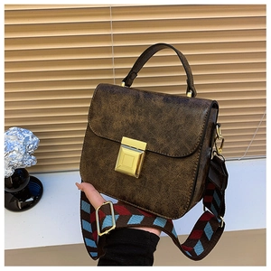 Detail of brown textured bag with gold square buckle and patterned wide strap