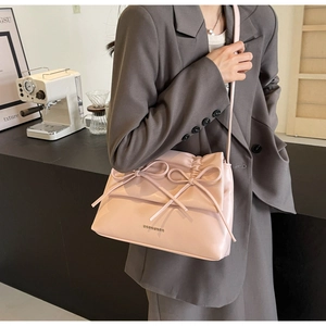 Close-up of the pink crossbody bag with twin bow accents and a smooth leather finish
