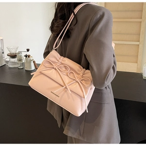 Detailed view of pink shoulder bag with decorative bows and premium leather texture