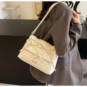 Detail of cream white tote bag featuring pleated design and decorative bows on shoulder strap