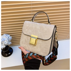 Detailed shot of beige vintage crossbody bag with crackle texture and wide woven strap