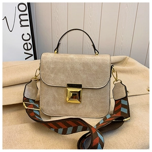 Close-up of cream textured crossbody bag with gold square buckle and jacquard strap