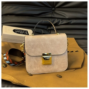 Detail of light pink textured handbag with square metal lock and woven shoulder strap