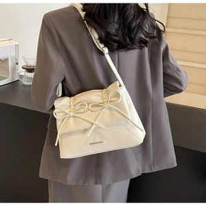 Detail of a beige leather shoulder bag featuring bow elements and pleated texture design