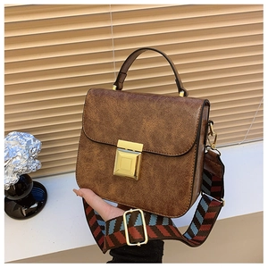 Detail of vintage brown textured crossbody bag with gold buckle and wide woven strap