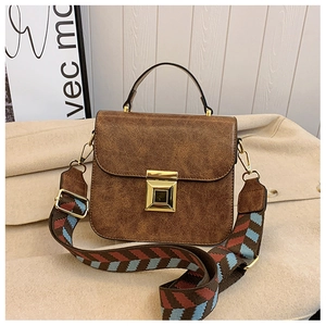 Detailed close-up of brown textured leather small square bag with ethnic wide strap