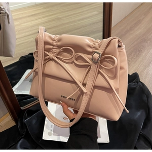 Detailed close-up of pink shoulder bag with bow decor, pleats and metal logo