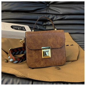 Detail of vintage brown shoulder bag with retro woven strap and golden metal lock