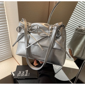 Detail view of metallic silver handbag featuring bow accents and Moromoro metal logo