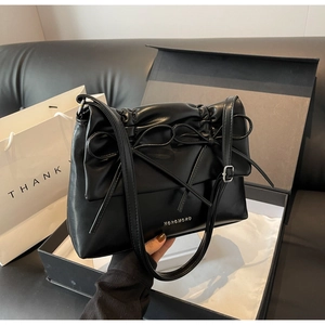 Detail of black PU leather bag with double bows and silver logo in a premium gift box