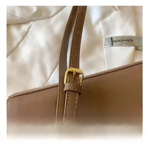 Detail of adjustable brown leather shoulder strap with gold buckle and fine stitching