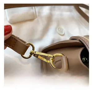 Close-up of golden metal clasp and brown leather strap with detailed stitching