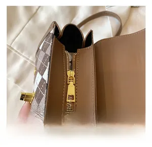 Close-up of golden metal zipper and stitching on checkered crossbody bag details