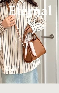 Close-up of brown lychee grain leather bucket bag featuring a decorative silk scarf