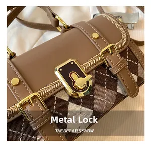 Detailed close-up of the vintage brown leather bag featuring a gold hardware lock buckle