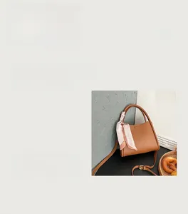 Détail du sac à main en cuir grainé caramel avec poignée décorée d'un foulard en soie