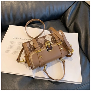 Macro shot of brown Argyle knit and leather拼接 crossbody bag on a white book prop