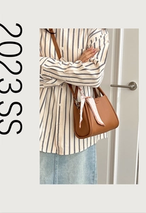 Détail du sac à main en cuir marron avec foulard en soie à fleurs sur l'anse