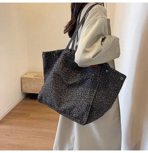 Detailed side view of a large leopard print canvas tote bag with front pocket and rivets