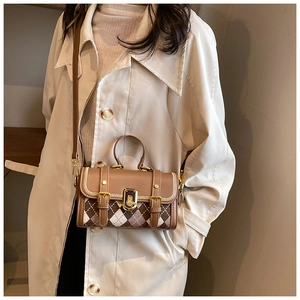 Detailed view of British style Argyle pattern crossbody bag worn with a trench coat