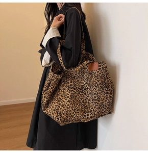 Detailed view of leopard print canvas tote bag with leather patch and studs on shoulder