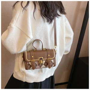 Detail of vintage brown leather Boston bag with diamond pattern and gold turn-lock closure