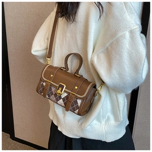 Detailed look at brown checkered crossbody bag on a model wearing a white knit sweater