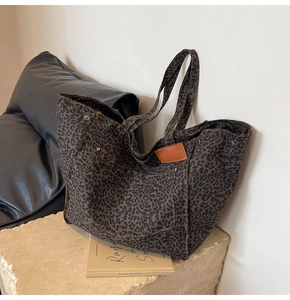 Detailed macro view of charcoal leopard print canvas tote bag with brown leather patches